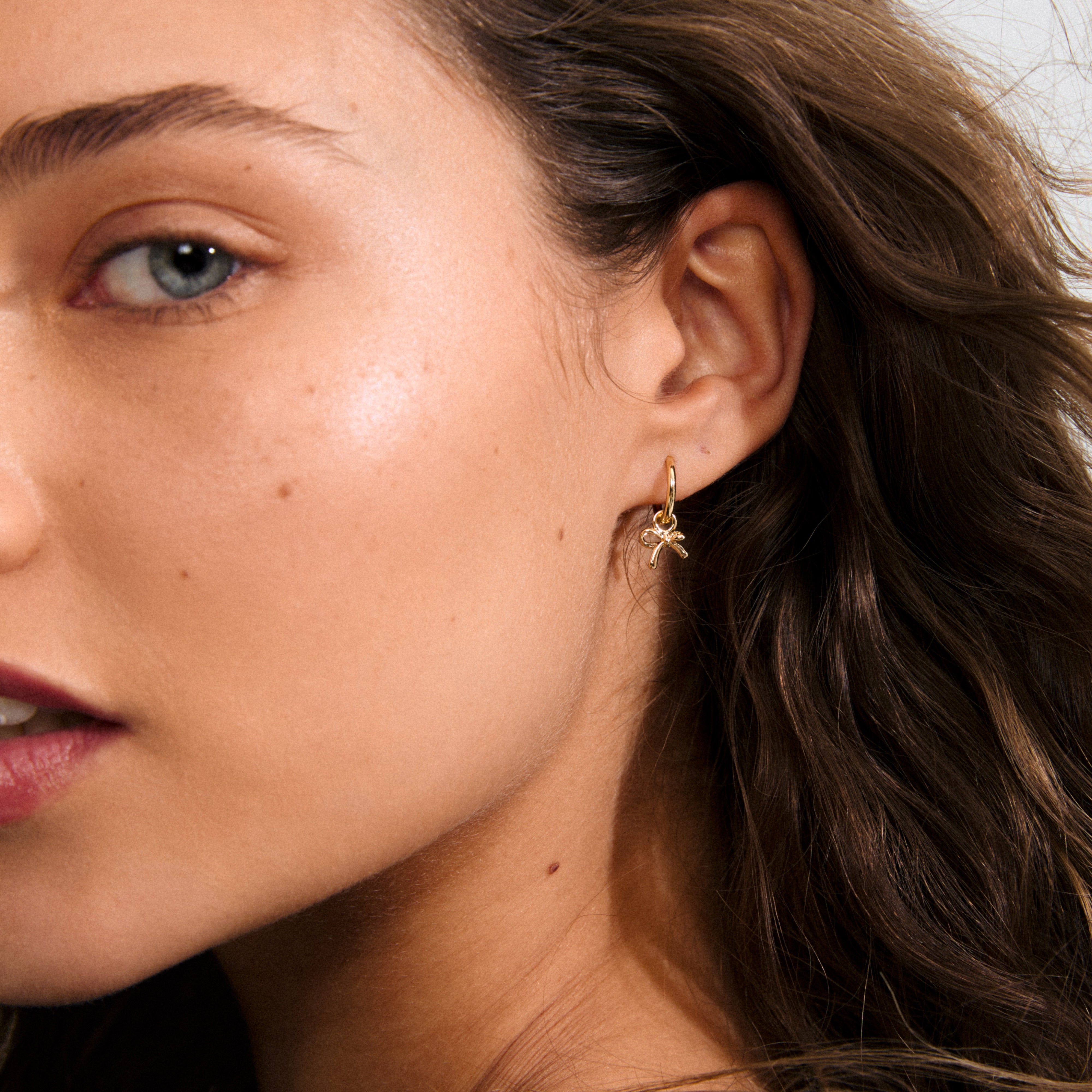 MURPHY single earring gold-plated, featuring a small huggie hoop with a charming bow pendant, crafted from 99% recycled material for a sweet, eco-friendly style.