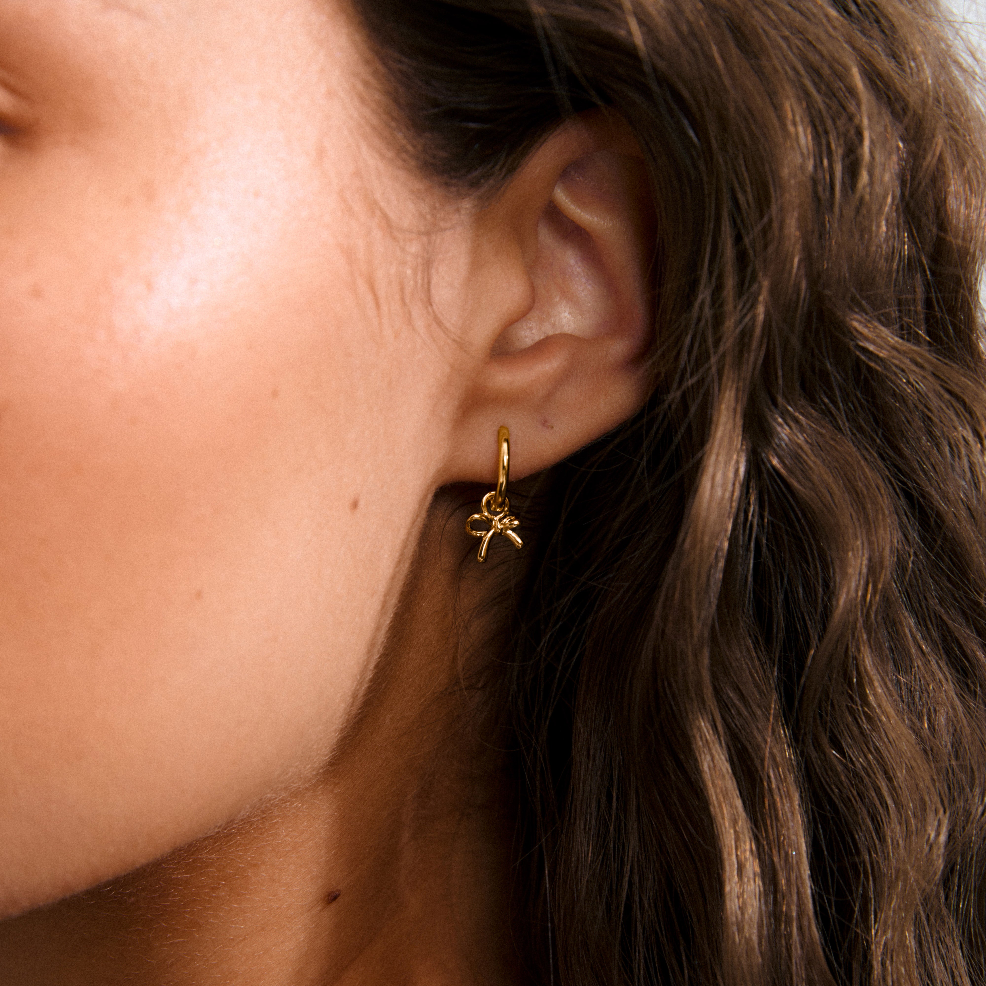 MURPHY single earring gold-plated: A charming huggie hoop featuring a tiny bow pendant, crafted from 99% recycled material with a convenient click clasp for easy wear.