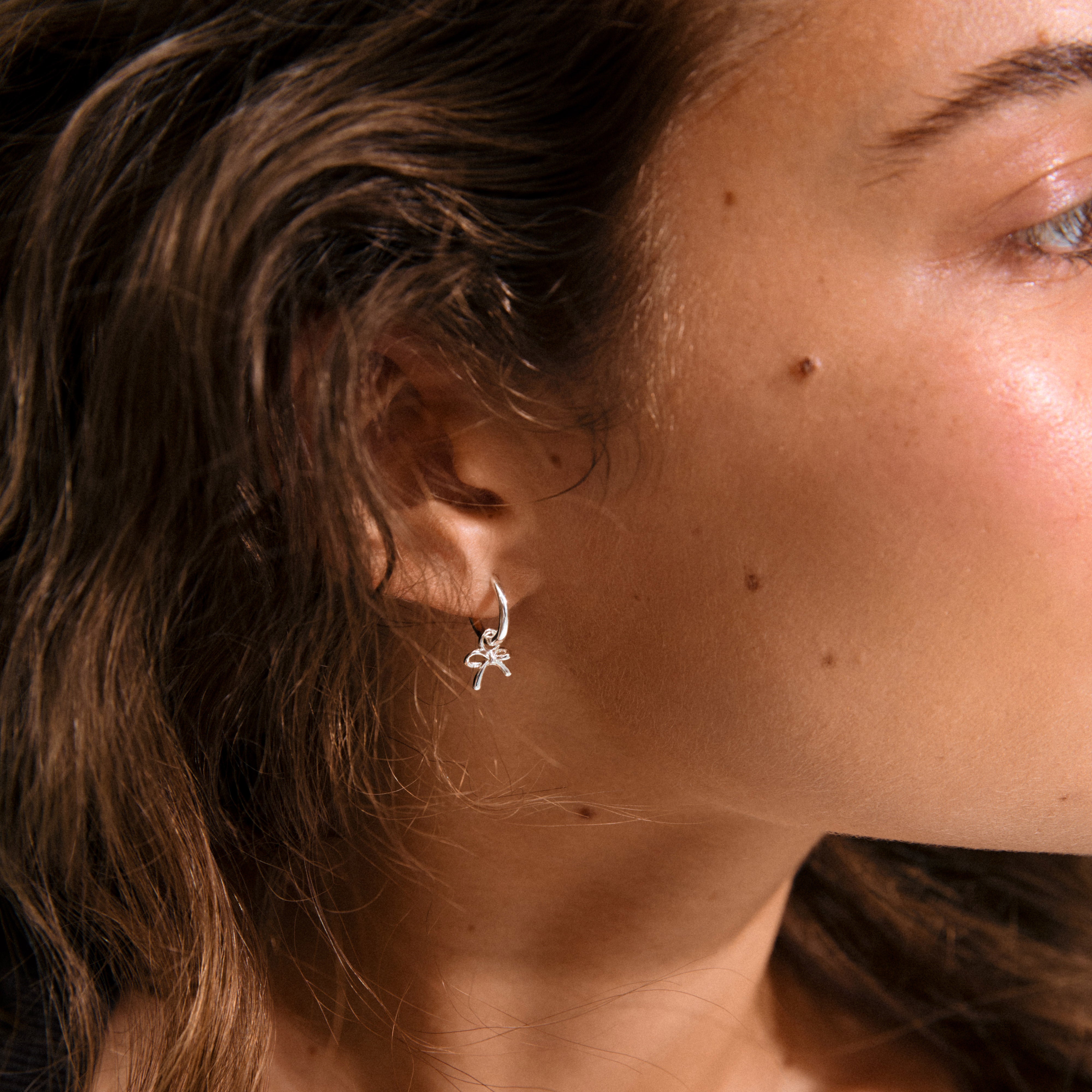 MURPHY single silver-plated earring with a tiny bow pendant, featuring a click clasp for easy wear, crafted from 99% recycled materials.