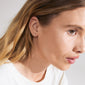 ARES single earring gold-plated, shaped like a leaf with Preciosa crystals, worn by a woman with blonde hair and a white shirt.