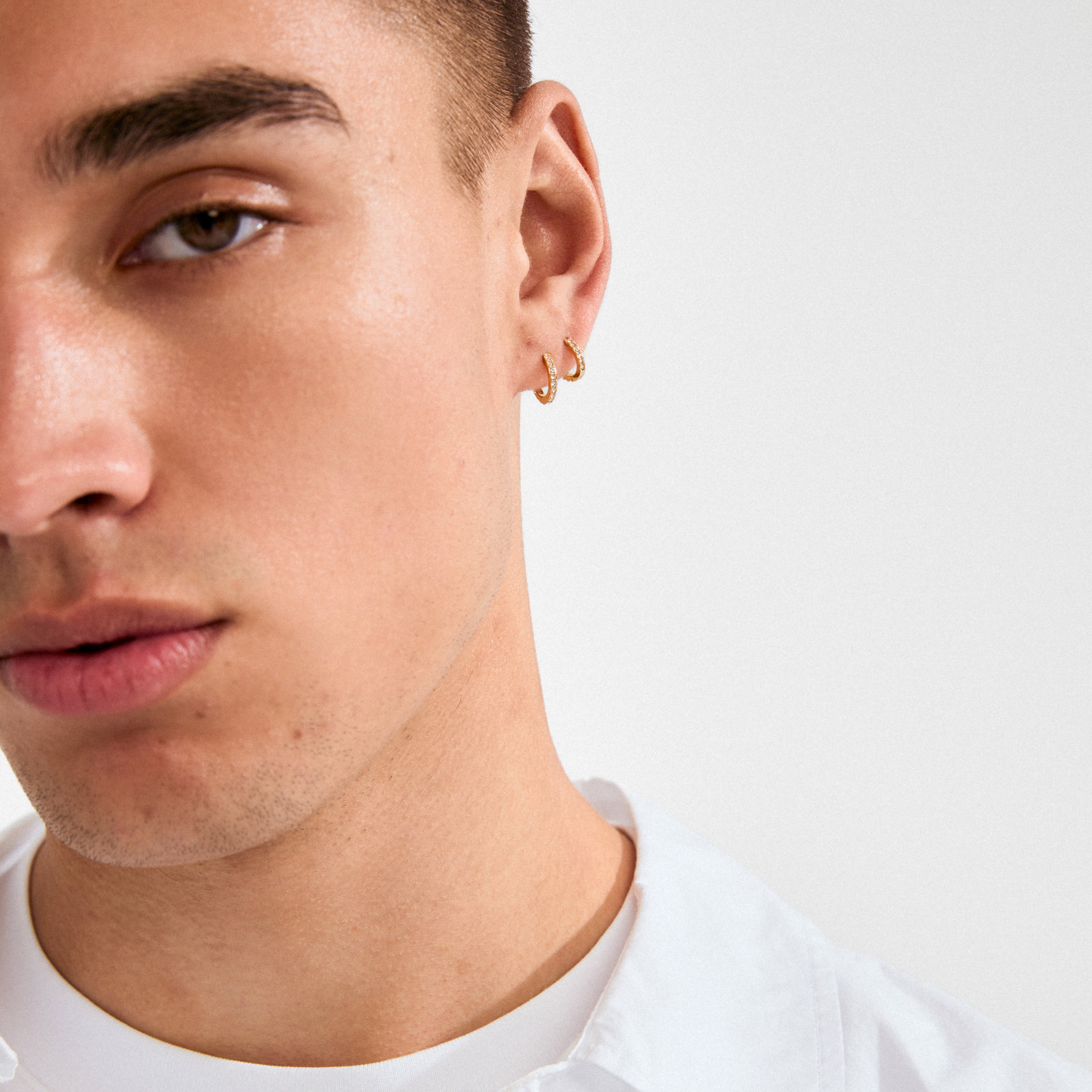 Young person wearing a ZOE single earring gold-plated with Preciosa crystals, showcasing a classic, versatile design suitable for mixing and matching styles.