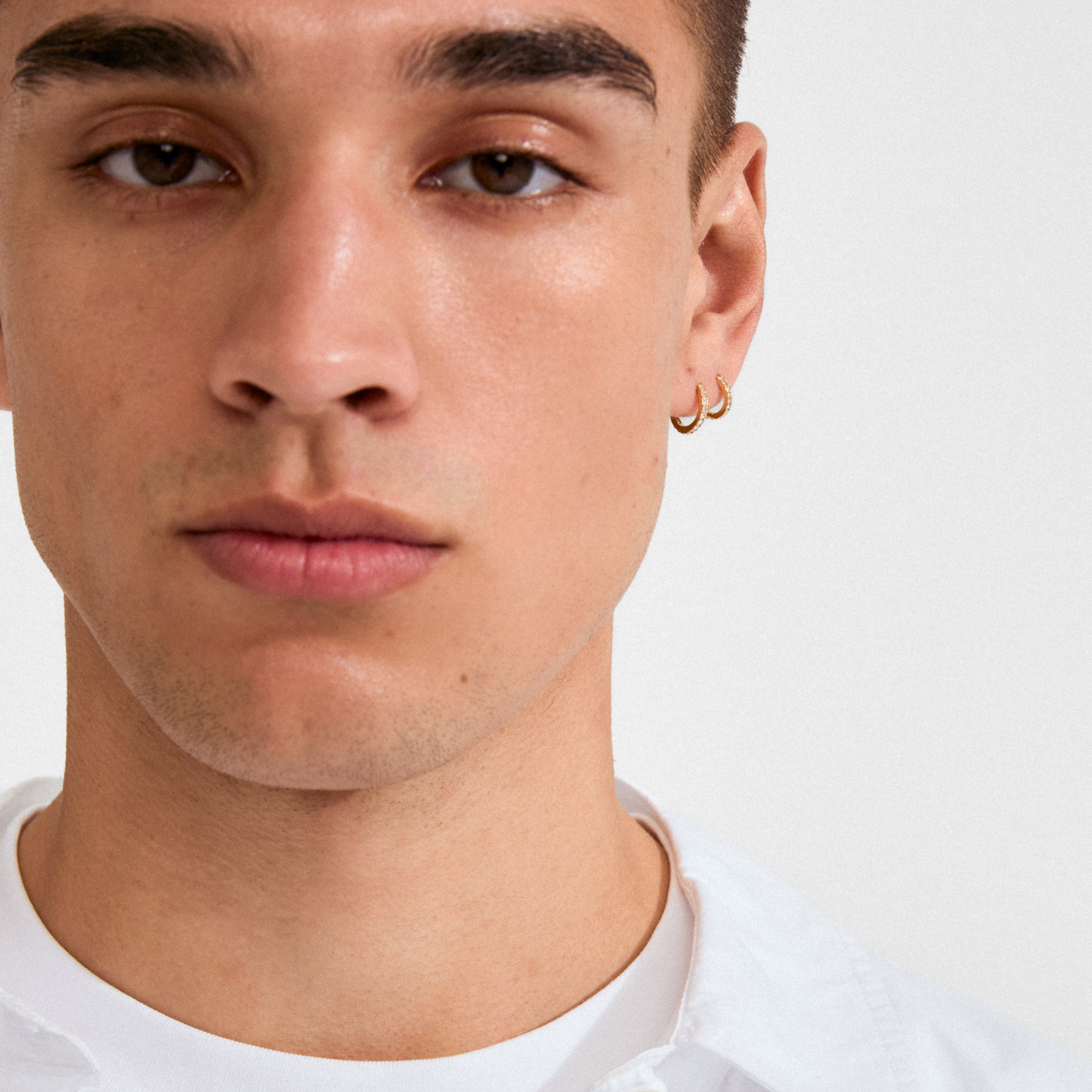 Young man wearing the ZOE single earring gold-plated, featuring small Preciosa crystals and a click clasp, highlighting its classic and versatile design.