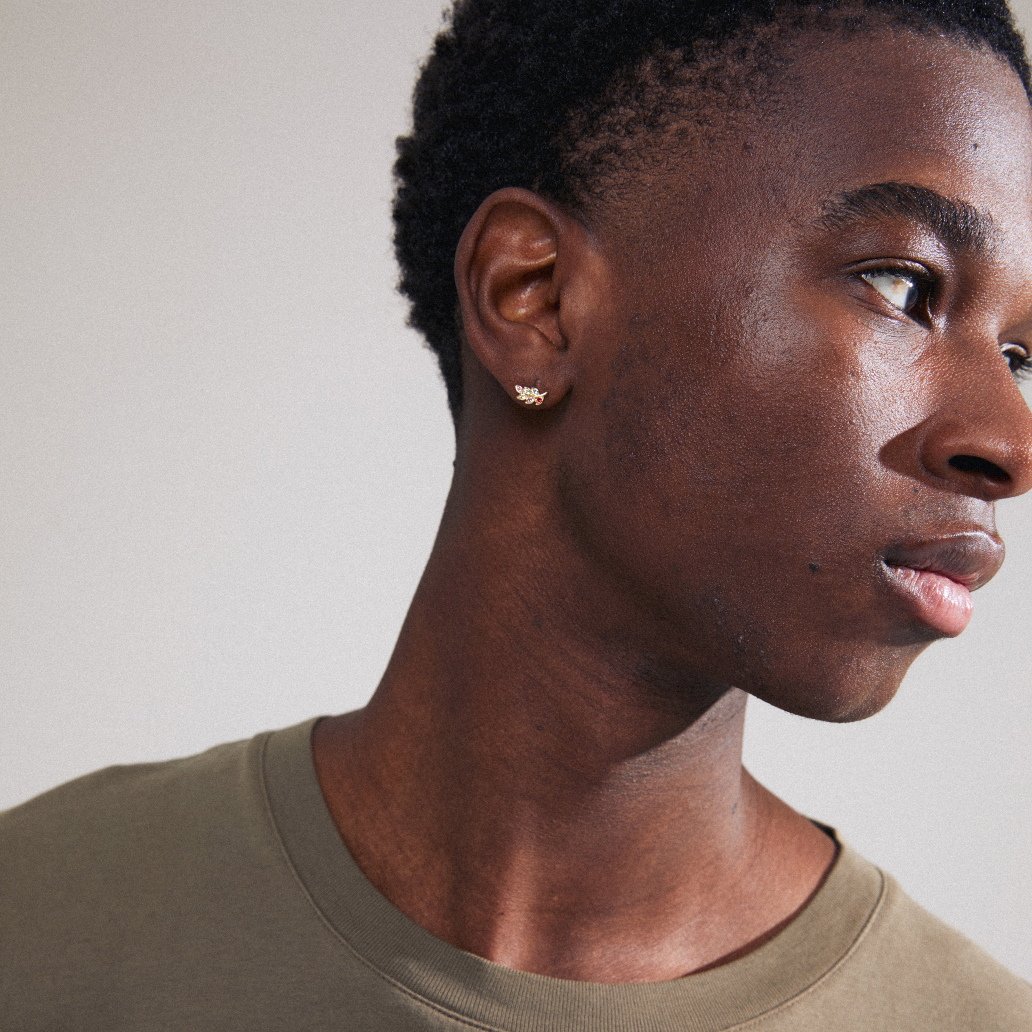 ARES single earring gold-plated, shaped like a leaf with colorful Preciosa crystals visible on a man's ear, highlighting intricate design and sparkle.
