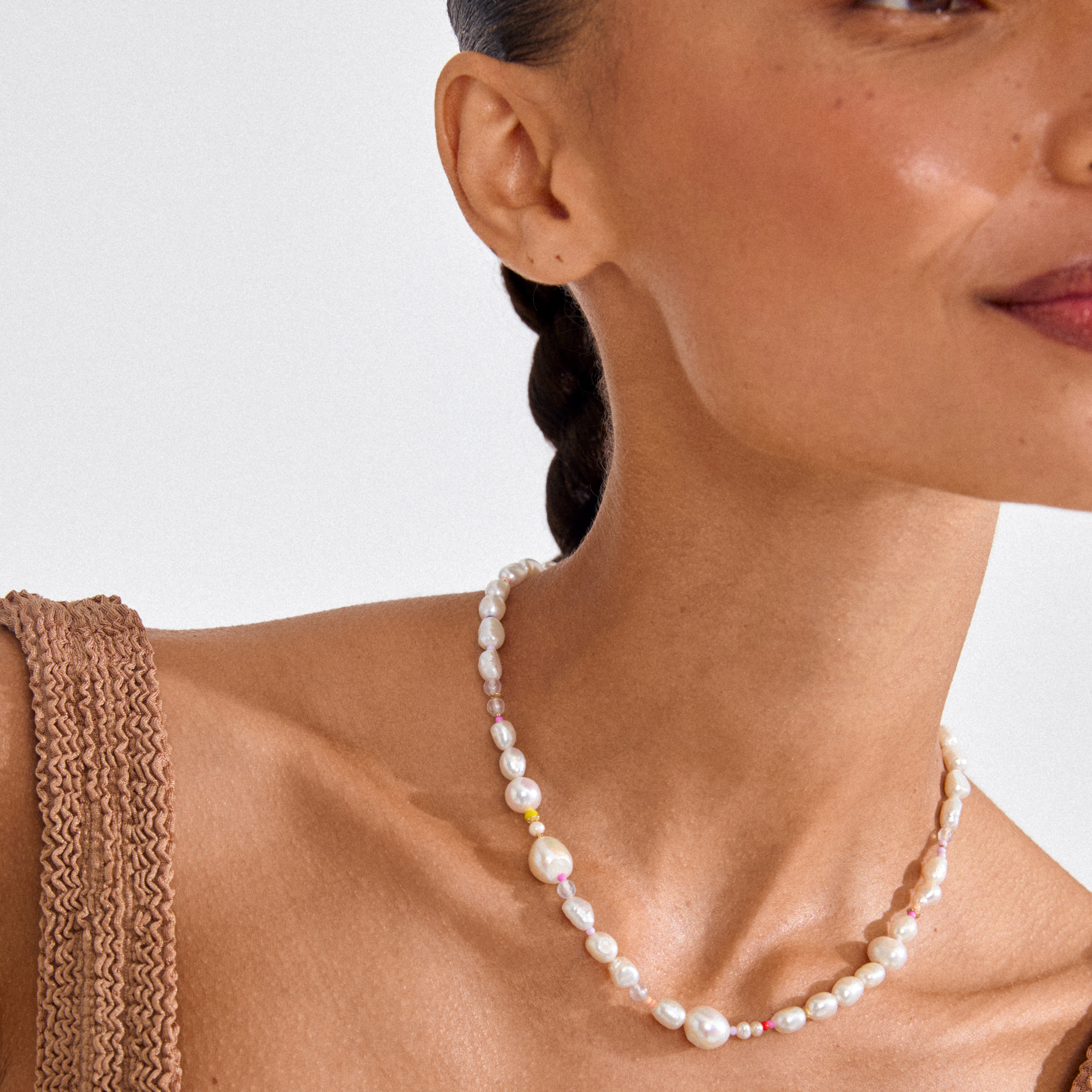 RAMONA freshwater pearl necklace gold-plated with baroque pearls and colorful spacer beads, worn by a woman in a textured earth-tone top.