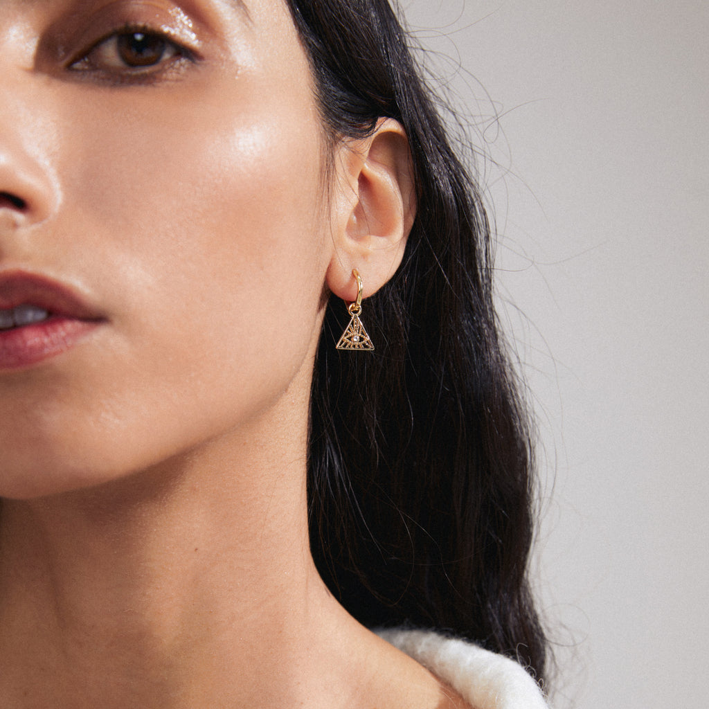 SIBYLLA single earring gold-plated, featuring a decorative triangle with Preciosa crystals, worn by a woman, showcasing Pilgrim's edgy, recycled, and personalized design.