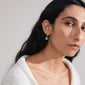 SIBYLLA single earring silver-plated, featuring an all-seeing eye motif within a triangle adorned with Preciosa crystals, worn by a woman with long hair.