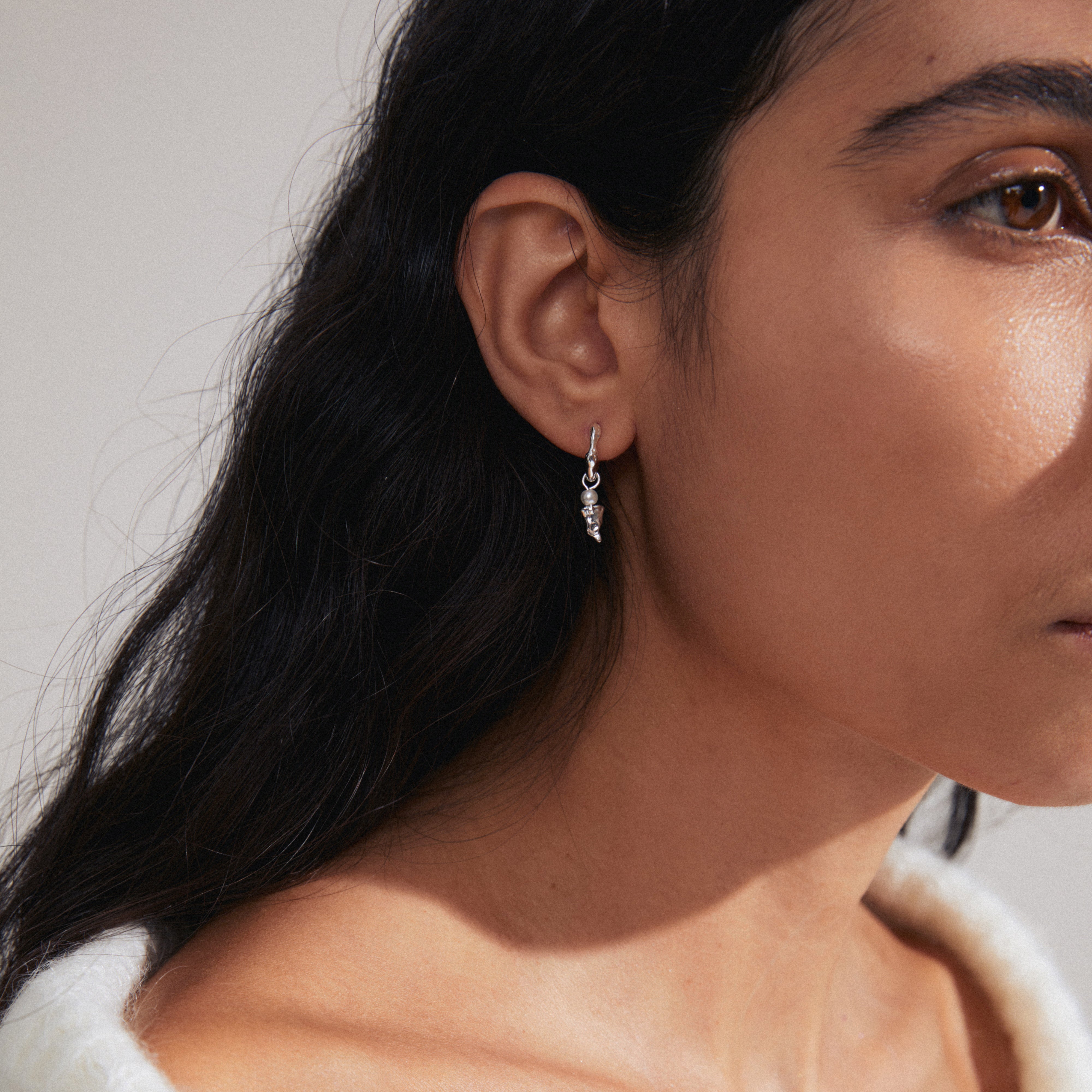 VASILKI single earring: silver-plated hoop with organic pendant and mother-of-pearl bead, worn by a woman with long hair, styled for asymmetrical look.