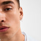 Young man wearing the VASILKI single earring, featuring a silver hoop with a dangling organic-shaped charm and glass bead, styled for a trendy asymmetrical look.
