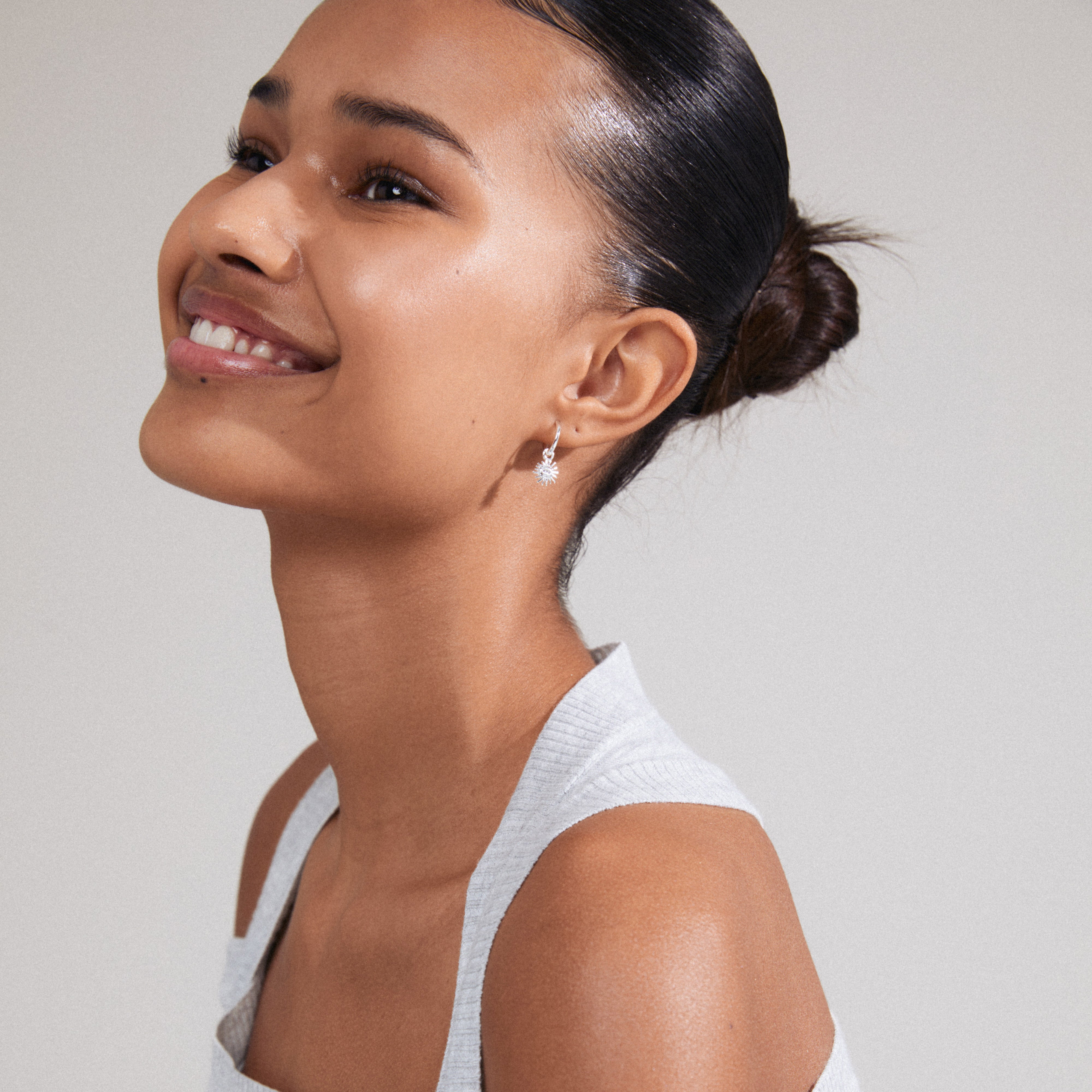 TITANIA single earring silver-plated, featuring a sun pendant with Preciosa crystal, worn by a woman with a stylish bun, embodying a luxe boho vibe.