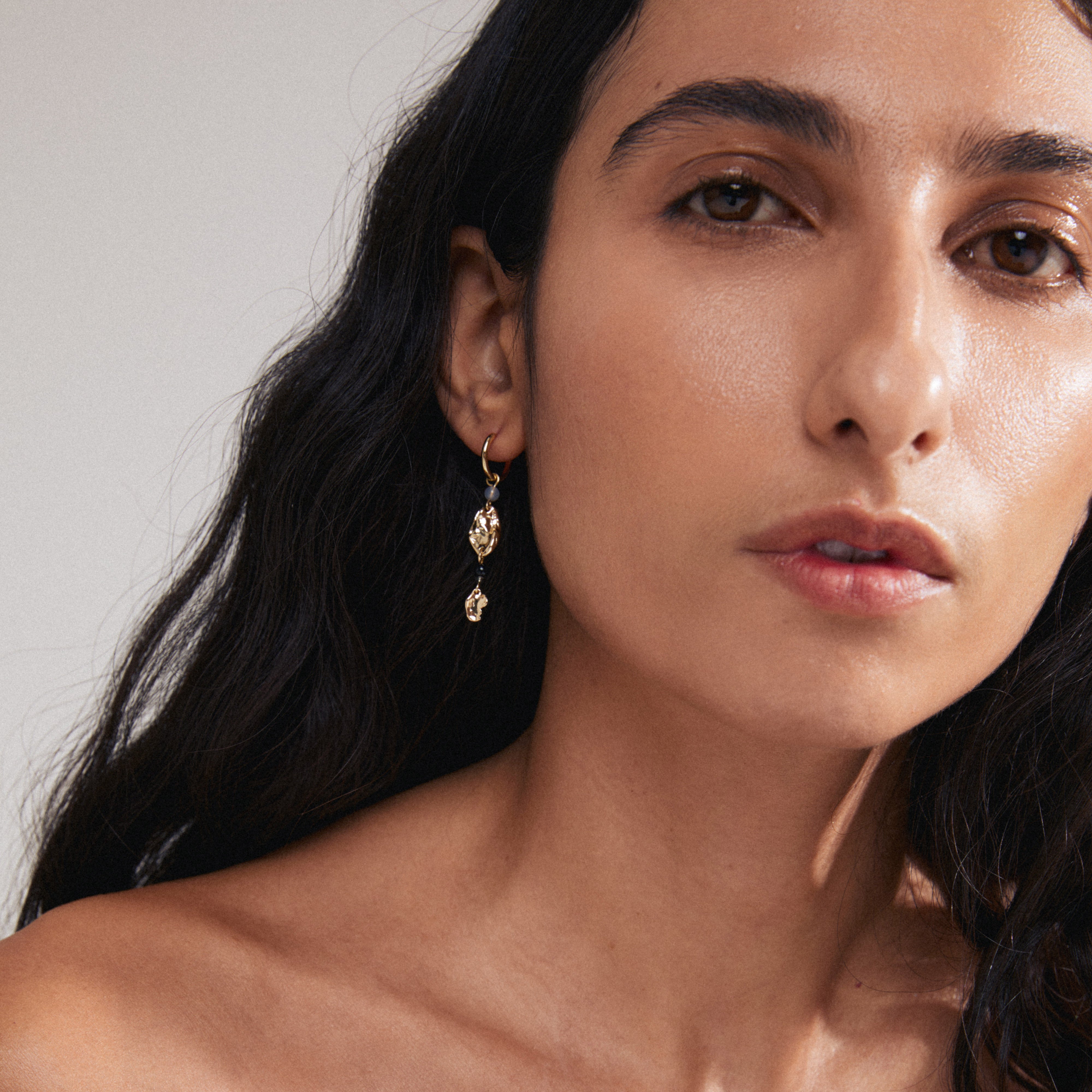 SARRA single earring gold-plated; close-up shows hoop with organic gold pendant and black agate, highlighting unique design and recycled material.