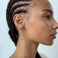 SIBYL single earring gold-plated, featuring a slender chain with colorful glass beads, worn by a woman with braided hair and a small diamond earring.
