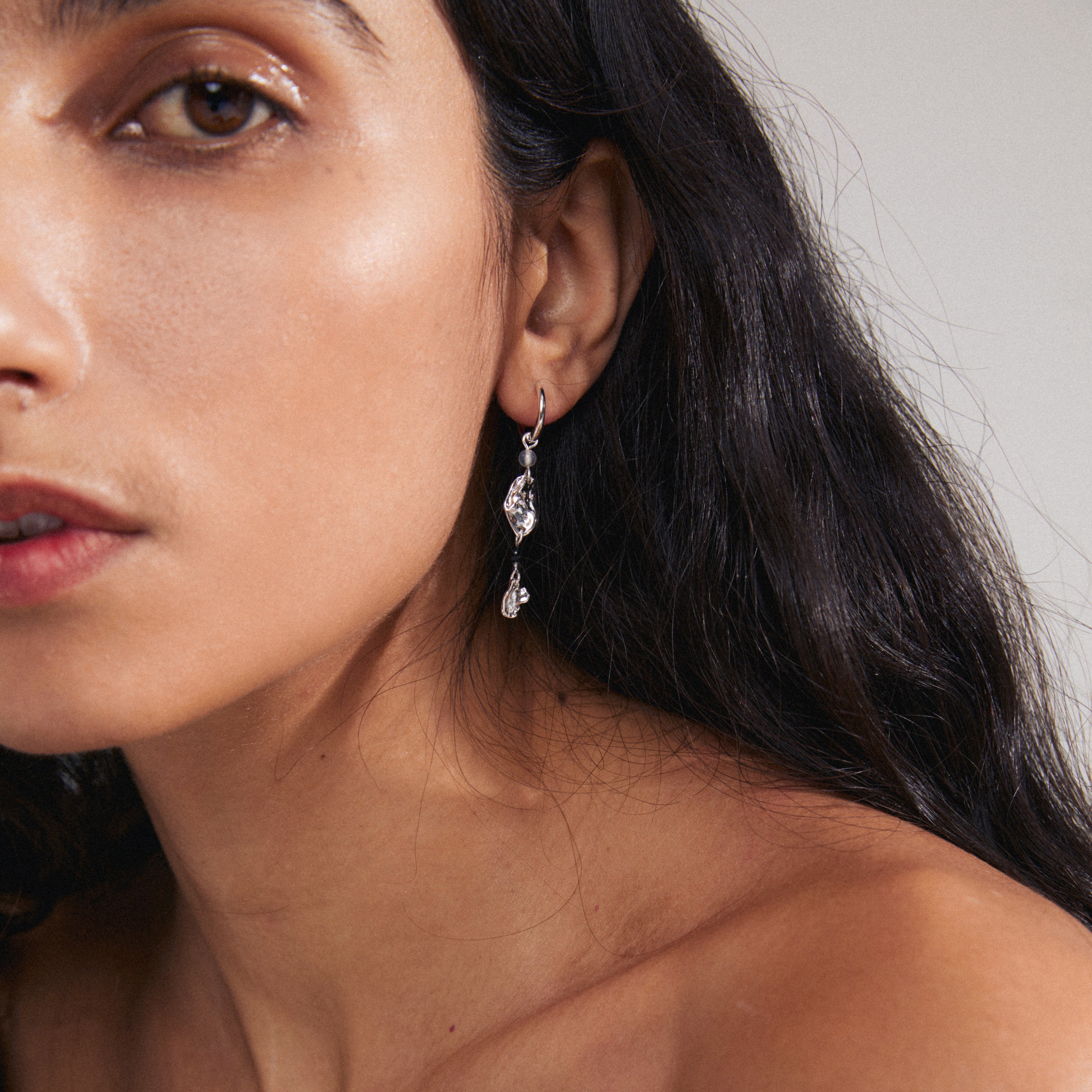SARRA single earring silver-plated with silver pendant and black agate detail, showcased close-up on a woman's ear for a stylish, asymmetrical look.