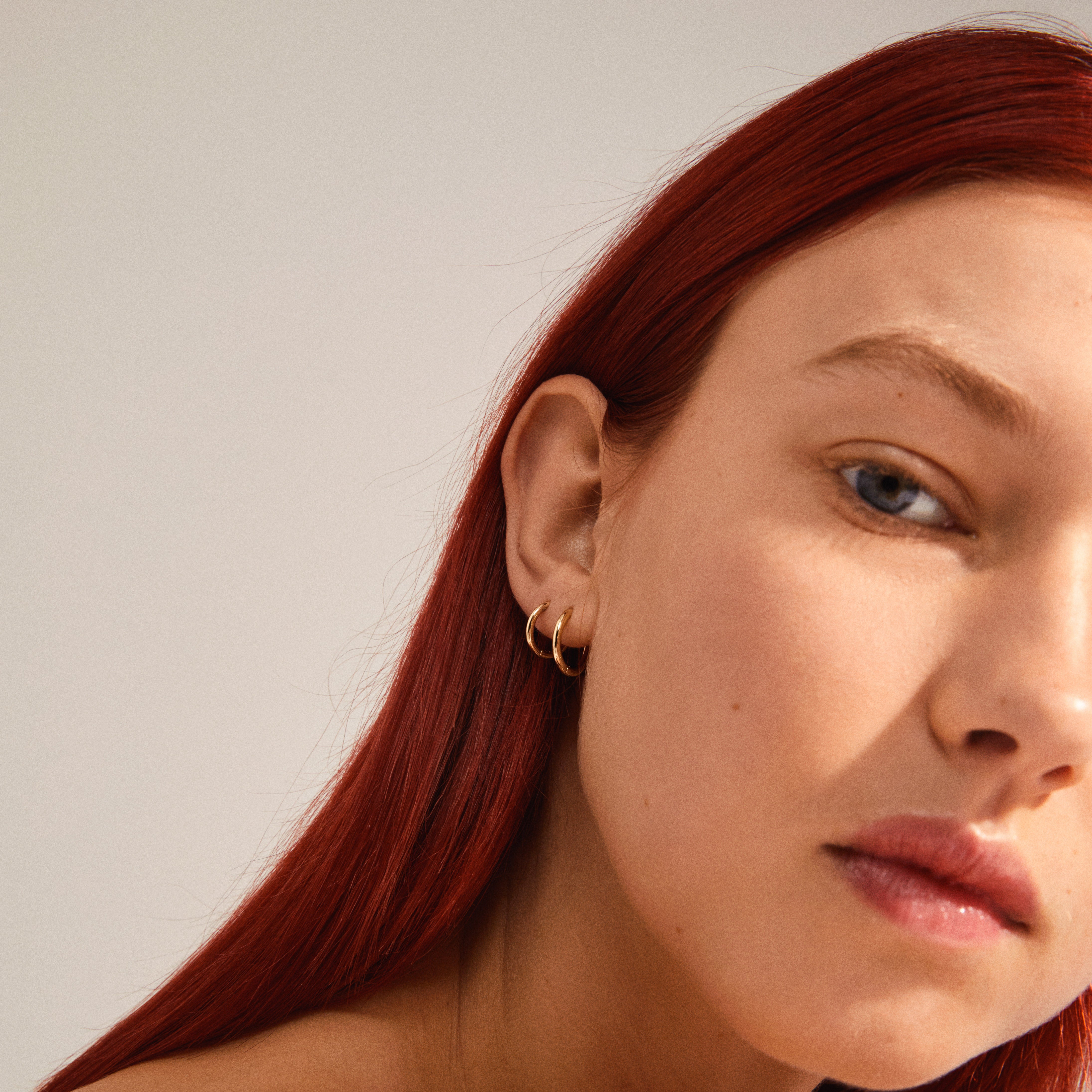 LEAF 2-in-1 set huggie hoops gold-plated: Close-up of woman wearing Pilgrim's recycled gold-plated mini hoop earrings, showcasing classic, everyday elegance.