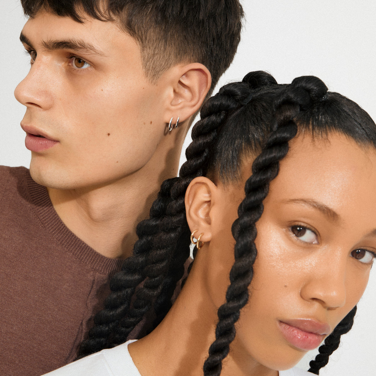 Two young adults showcase Pilgrim's LEAF 2-in-1 set huggie hoops gold-plated, both wearing small hoop earrings highlighting timeless style and sustainable craftsmanship.