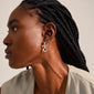 Close-up of a woman wearing Pilgrim's LEAF coin hoops, silver-plated earrings with decorative coin pendants, highlighting the unique bohemian style.