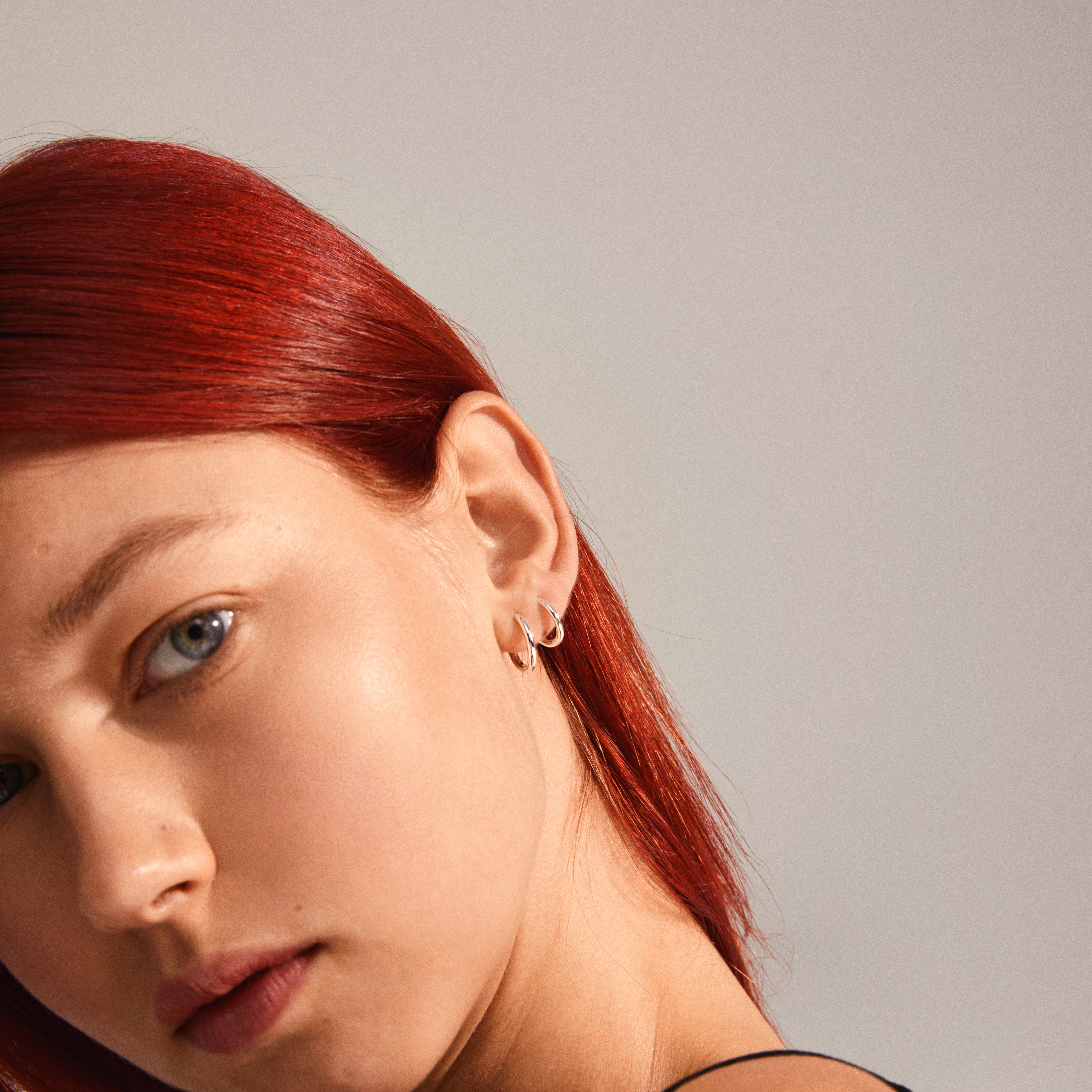 LEAF 2-in-1 set huggie hoops, silver-plated, worn by a red-haired woman. Features include four mini hoops with click locks, highlighting timeless style.