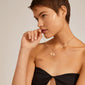 Woman wearing a black dress showcases the CHARM love pendant gold-plated, featuring two heart charms, ideal for personalizing a necklace or bracelet.