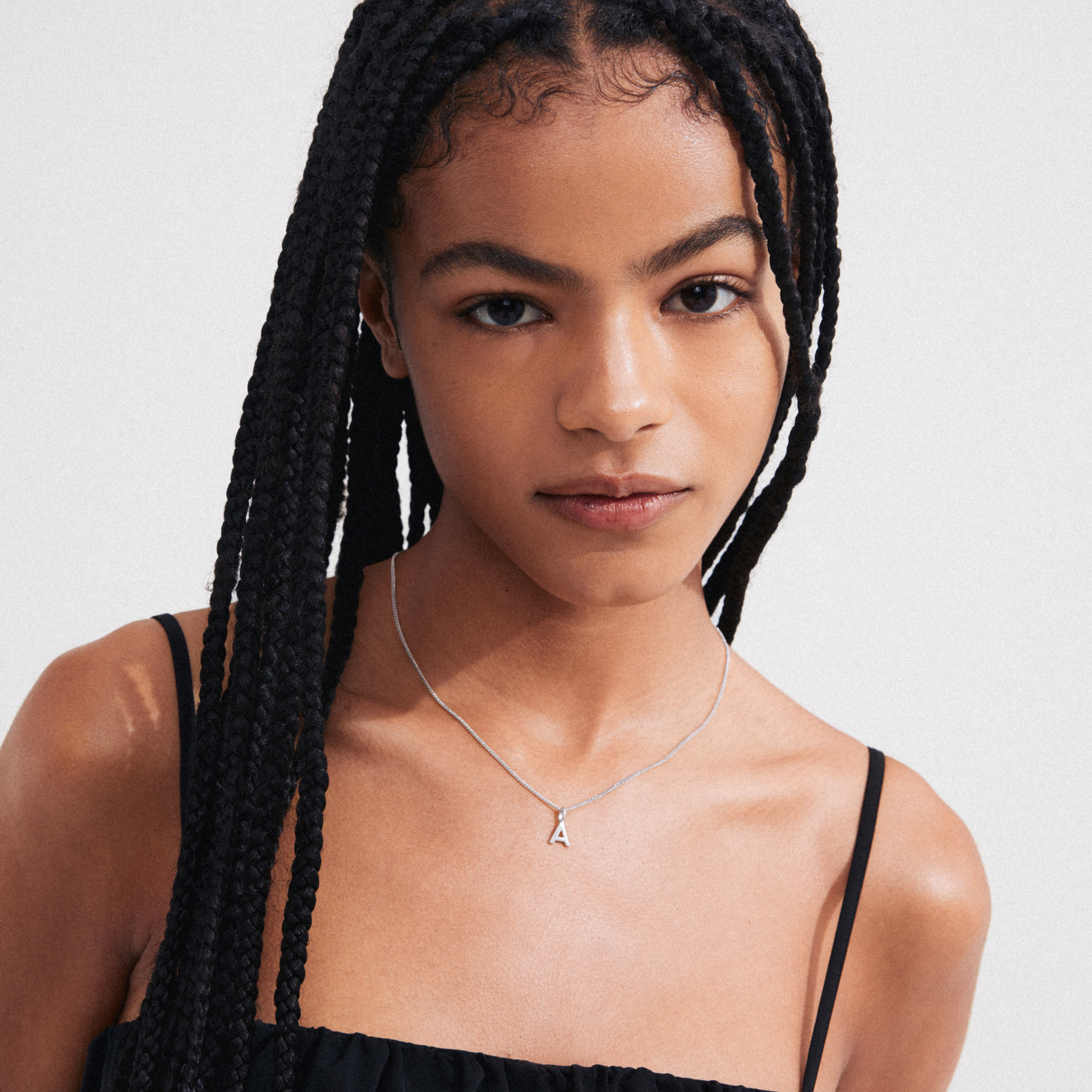 Young woman wearing the CHARM necklace with an “A” pendant, silver-plated, showcasing personalized elegance. Ideal for trendsetters seeking unique, meaningful jewellery from Pilgrim.