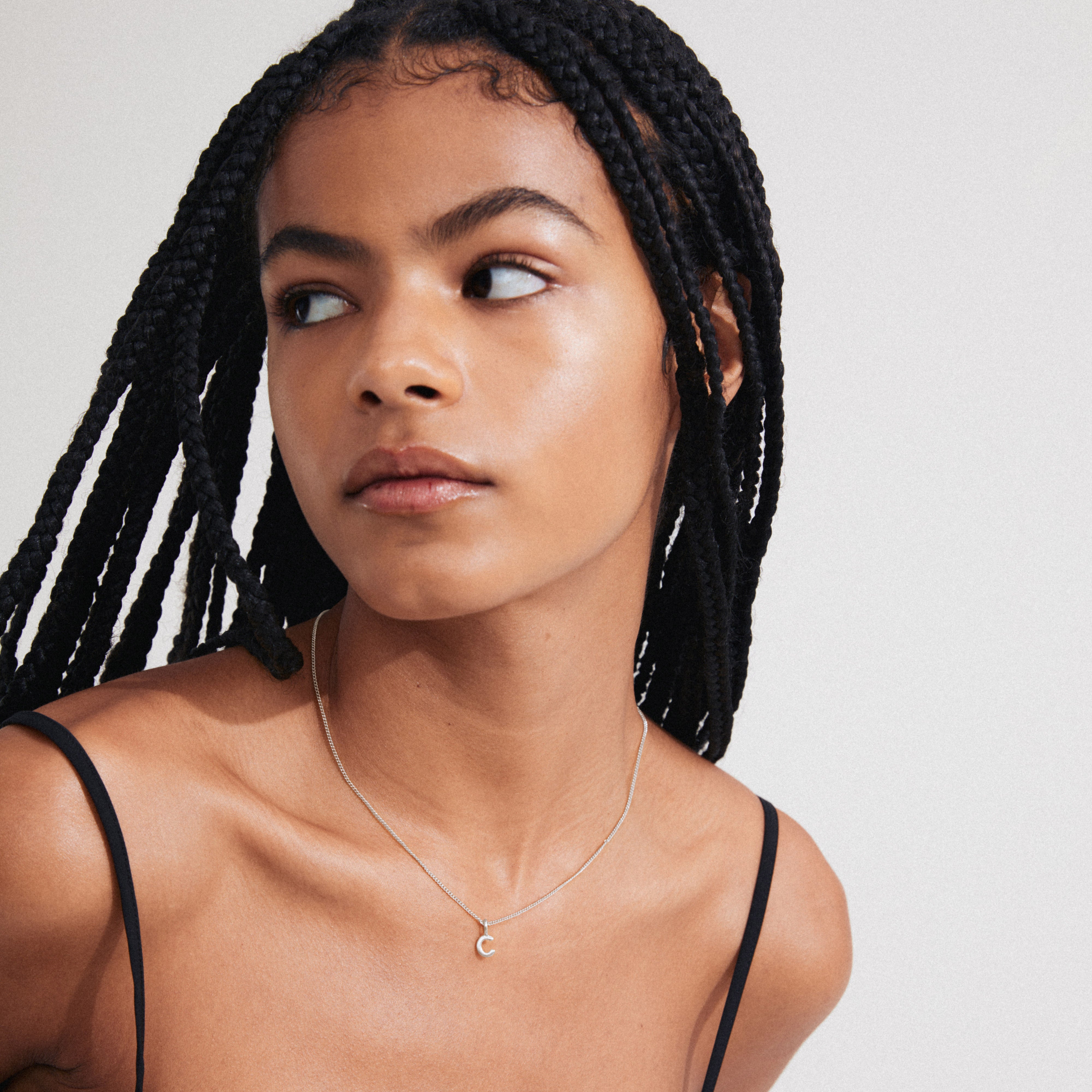 Young woman wearing a CHARM necklace with a silver-plated C pendant, showcasing personalization and style. Perfect for adding a bespoke touch to any look.