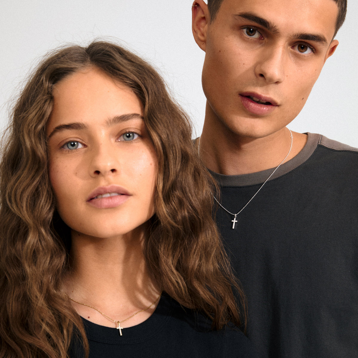 Silver-plated mini cross pendant with sparkling crystals, worn by a man, reflecting personal style and symbolic statement. Perfect for necklaces, bracelets, or hoops.