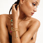 Woman wearing a gold-plated CHARM pendant A, complemented by earrings and a necklace, highlighting Pilgrim's unique, personalized, and eco-friendly jewelry style.