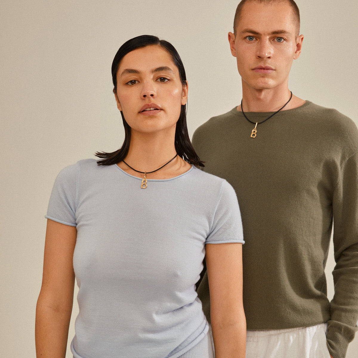Man and woman wearing Pilgrim's CHARM pendant B, gold-plated, showcasing its rustic design and personalized styling potential.