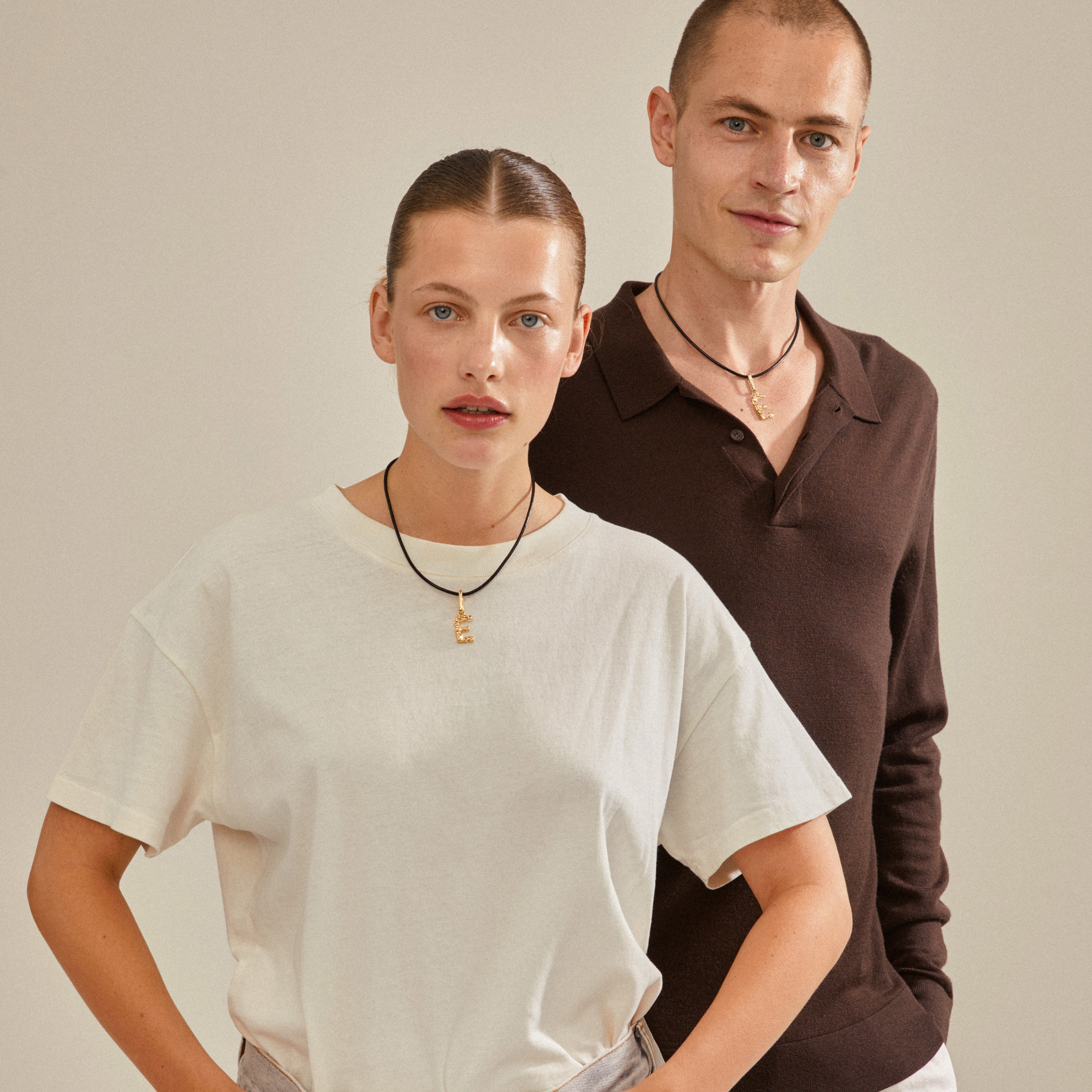 Gold-plated CHARM pendant E by Pilgrim, worn by a woman, showcasing a personalized style with rustic design and sustainable materials.