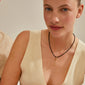 Woman smiling, wearing a Pilgrim CHARM pendant J in gold-plated finish, showcasing a unique, personalized style with a focus on sustainable fashion.