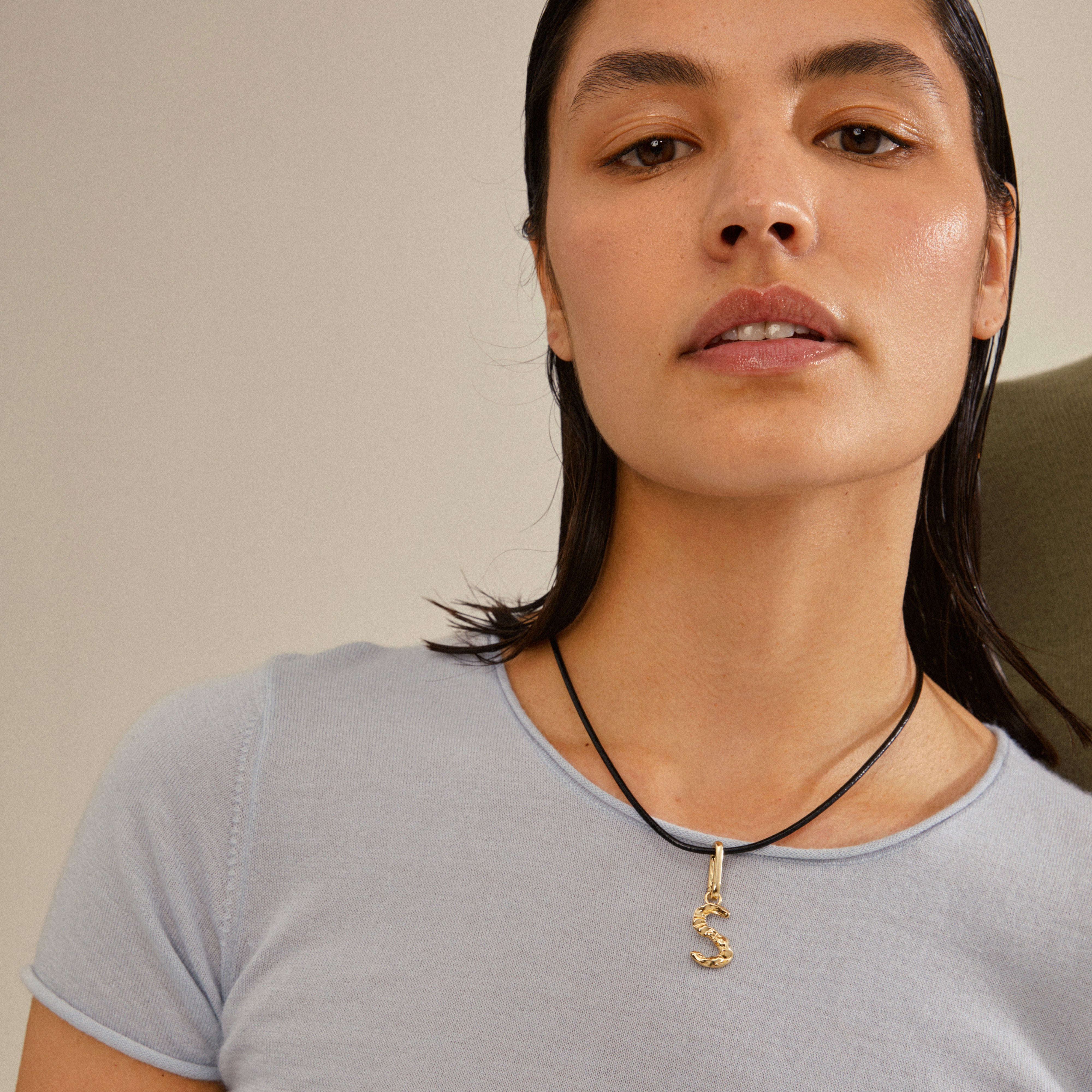 Close-up of a woman wearing a CHARM pendant S, gold-plated, showcasing Pilgrim's rustic, personalized jewelry design.
