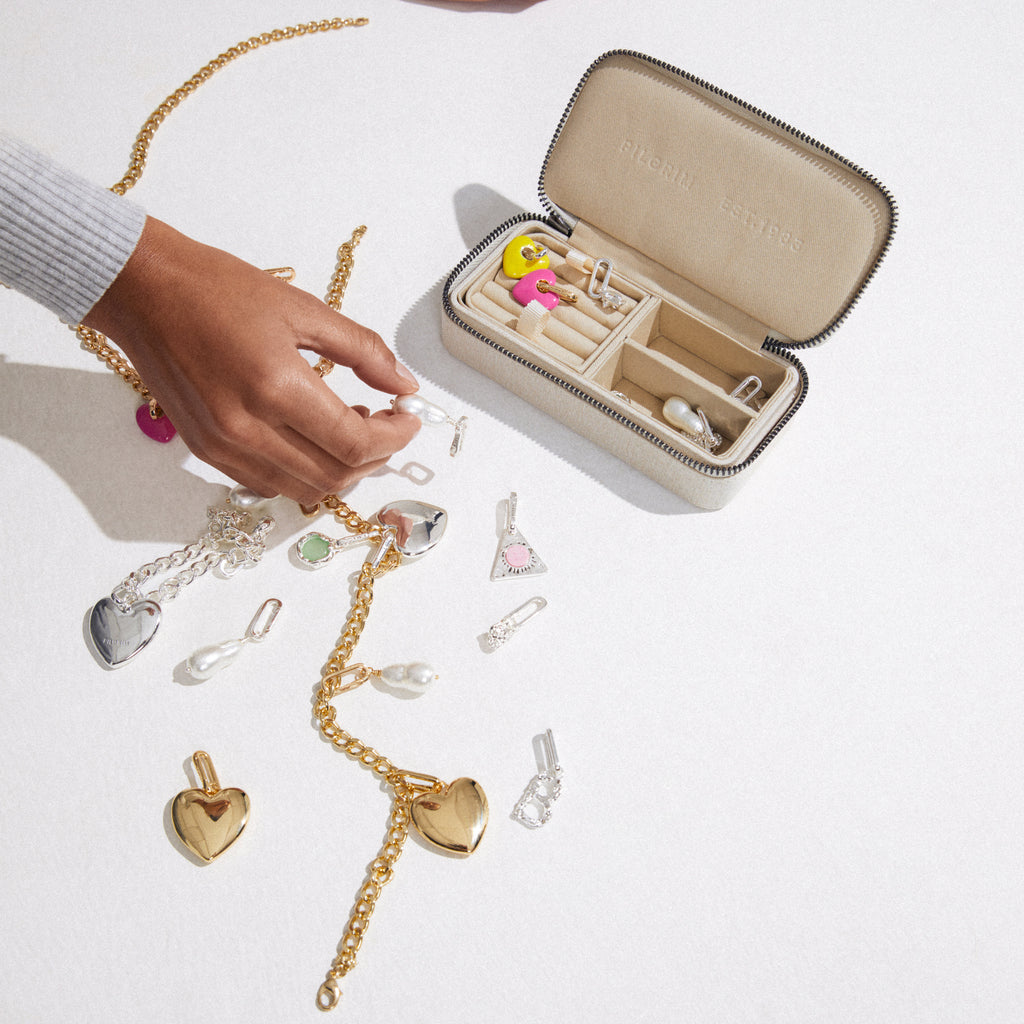 Hand holding a jewelry box containing the CHARM curb necklace gold-plated, featuring an adjustable gold-plated curb chain for adding charms, reflecting an edgy, urban style.