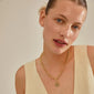 Woman wearing gold-plated CHARM coin pendant by Pilgrim, showcasing a heart-shaped design, ideal for personal style and sustainable fashion choices.