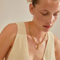 Woman wearing a gold-plated CHARM stone pendant from Pilgrim, highlighting Scandinavian craftsmanship and sustainable fashion with a unique, personalized style.