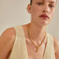 Woman wearing Pilgrim's CHARM stone pendant, gold-plated, showcasing a rustic, personalized look with a recycled material focus. Perfect for a unique, eco-conscious style statement.