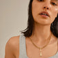 Woman with wet hair wearing a gold-plated CHARM tag pendant necklace, showcasing a rustic design ideal for personalized styling with recycled materials.