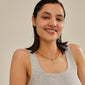 Woman smiling, wearing Pilgrim's CHARM love pendant, gold-plated, showcasing a personal, stylish touch with recycled material, perfect for trendy, personalized styling.