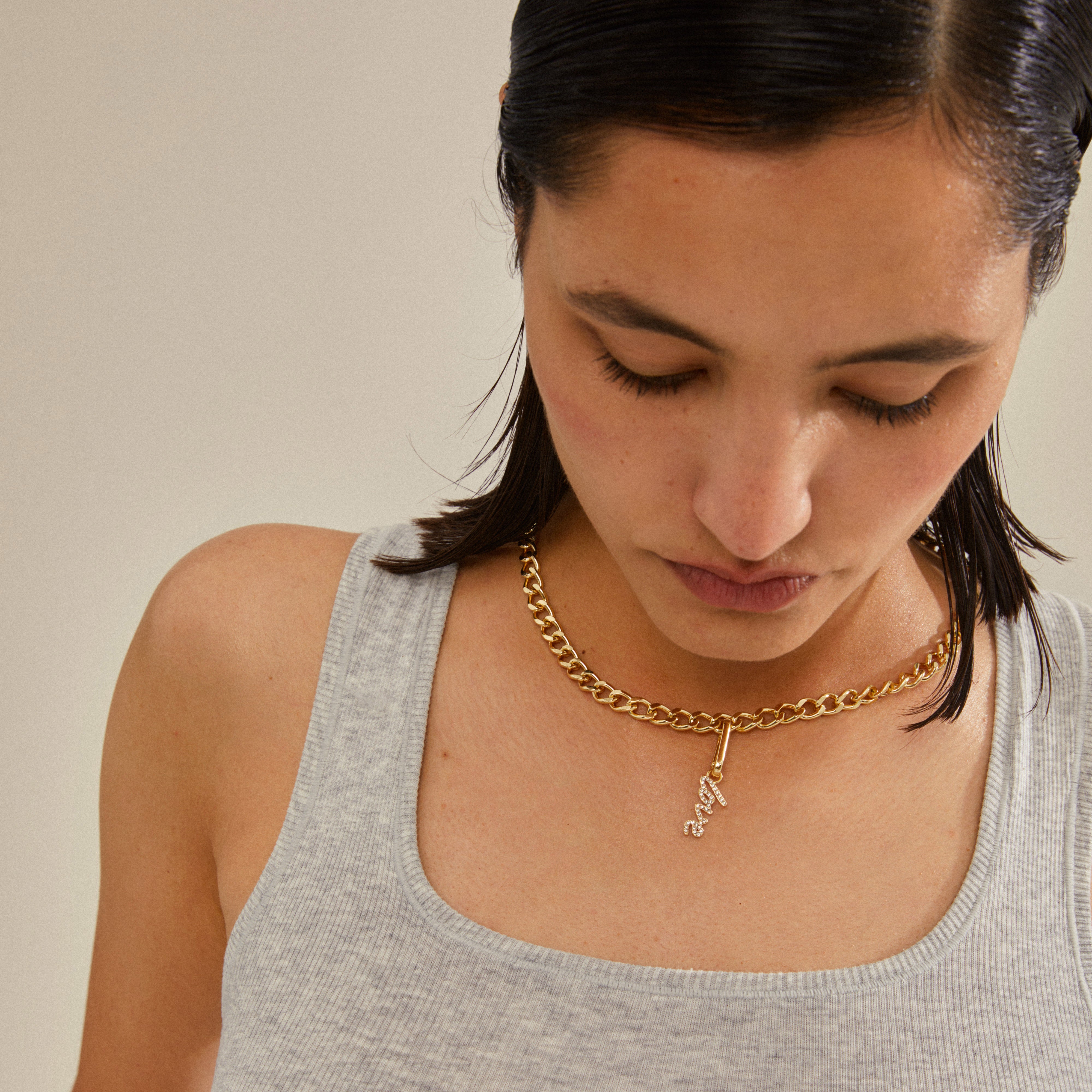 Woman wearing Pilgrim's CHARM love pendant, gold-plated, highlighting its elegance and personalized style potential with a close-up on the necklace and her neck.