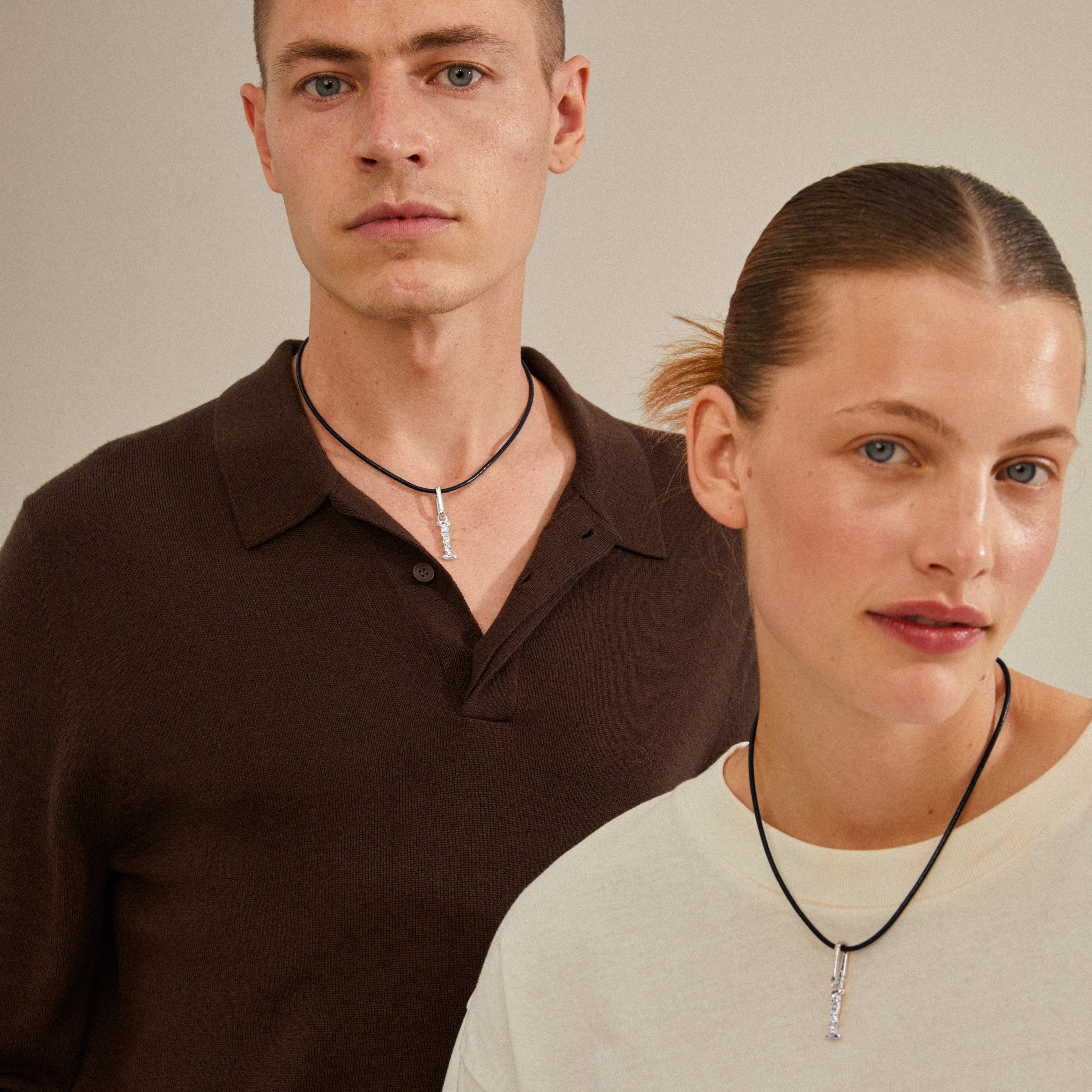 Man and woman wearing CHARM pendant I, silver-plated. The necklaces are styled with other pendants for a personalized look, reflecting Pilgrim's Scandinavian quality.
