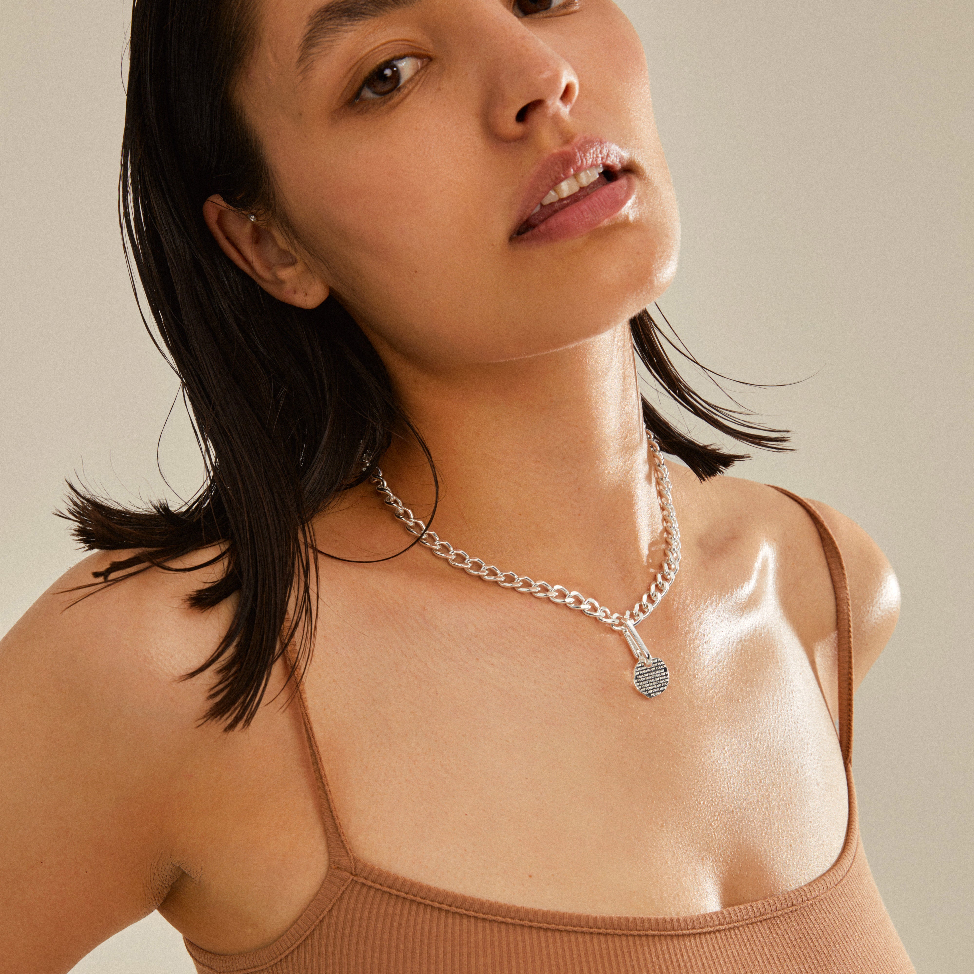 Woman wearing Pilgrim's CHARM coin pendant, silver-plated, showcasing its rustic design on her neck, emphasizing personalized style with the recycled material pendant.