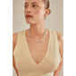 Woman wearing a CHARM stone pendant, silver-plated, on a necklace, showcasing Pilgrim's unique, sustainable design with a focus on personalization and style.