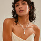 Woman wearing a white dress and wet hair, showcasing Pilgrim's CHARM pearl pendant, silver-plated, elegantly resting on her neck, highlighting Scandinavian craftsmanship.