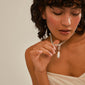 Woman holding a Pilgrim CHARM pearl pendant, silver-plated, around her neck, showcasing its elegant design as a statement jewelry piece.