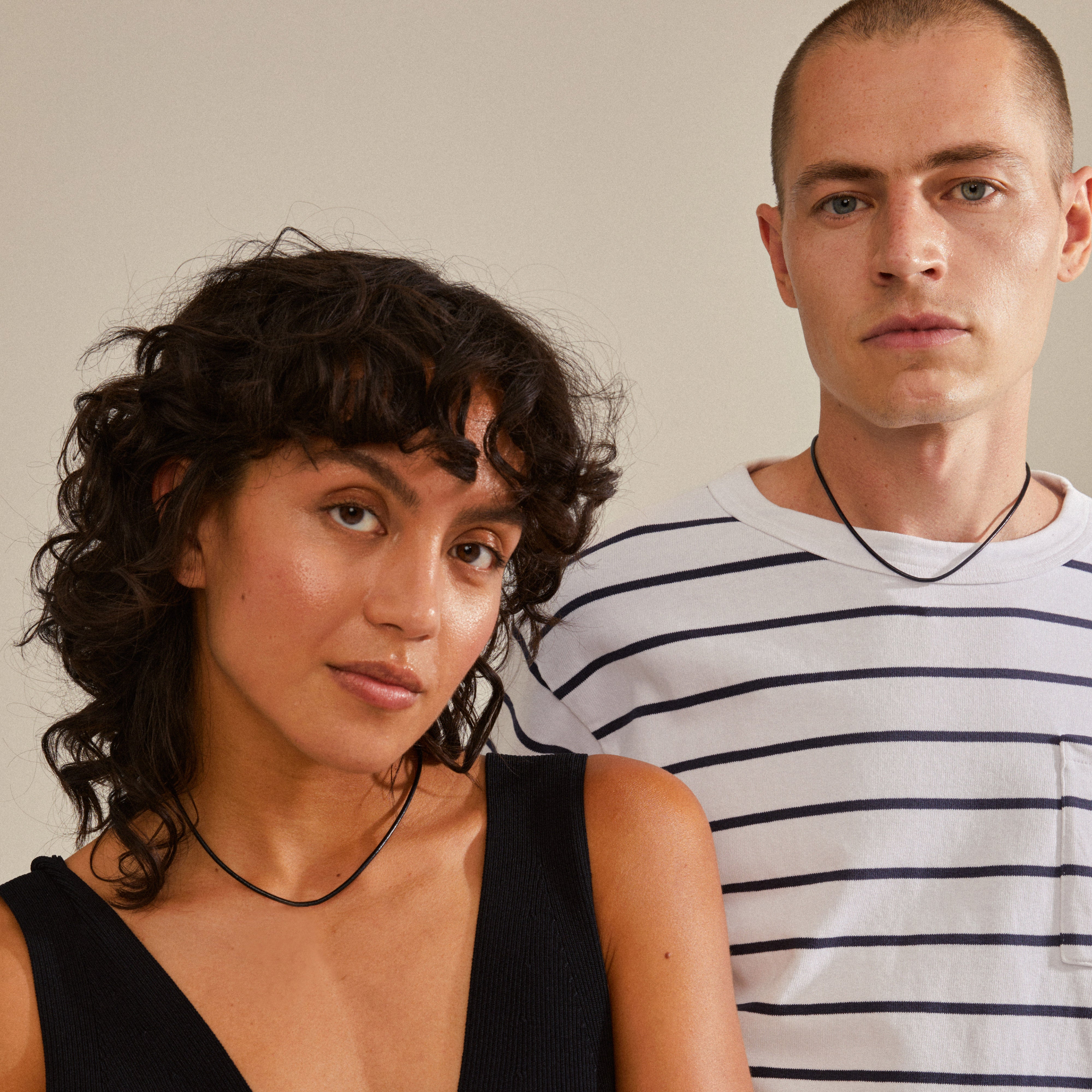 Man and woman showcasing the CHARM leather cord necklace, black/silver-plated, styled simply, emphasizing its adjustable length and natural, earthy appeal.