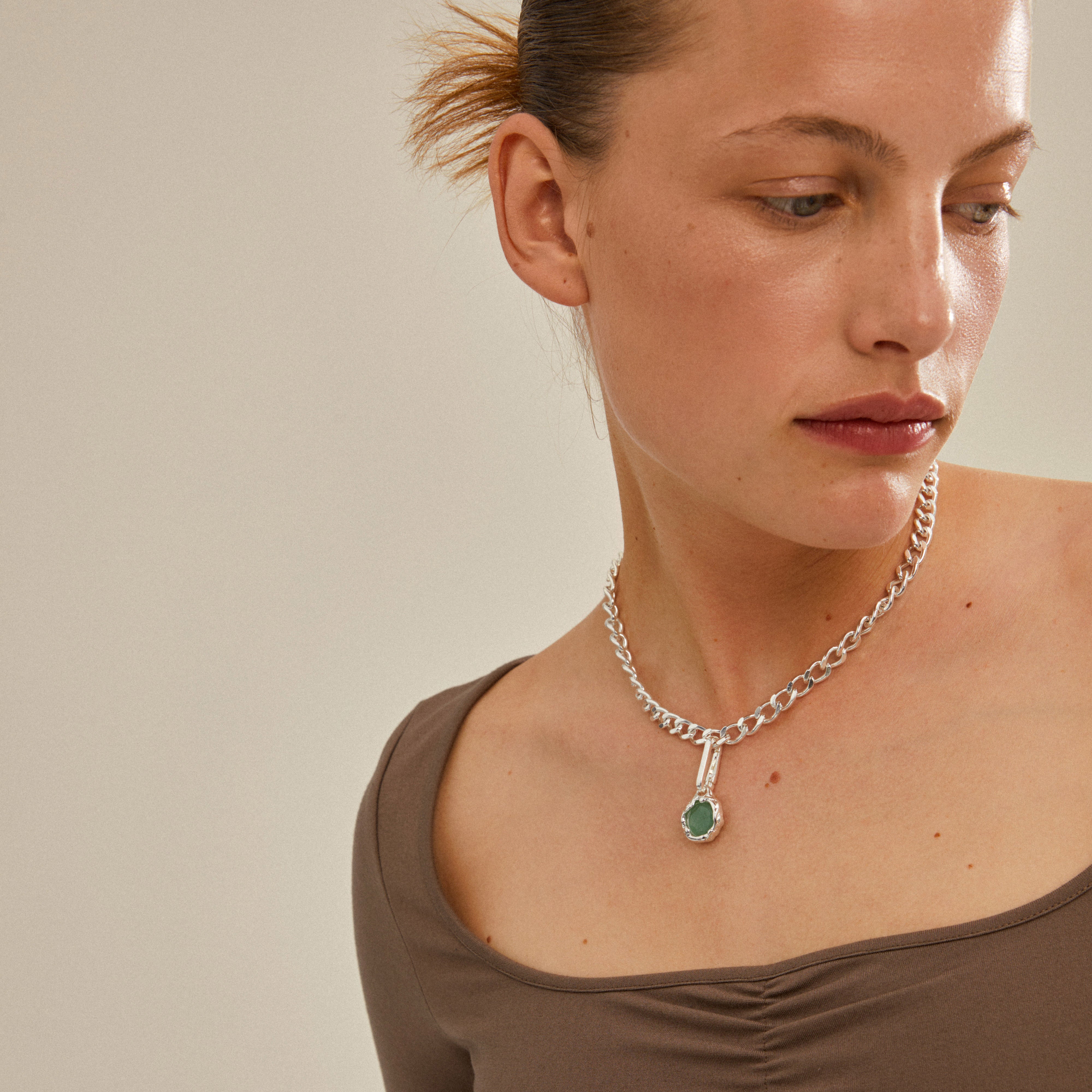 Woman wearing a CHARM natural pendant, green/silver-plated, showcasing a silver-plated aventurine charm on a necklace, highlighting Pilgrim's trendy, sustainable jewellery.