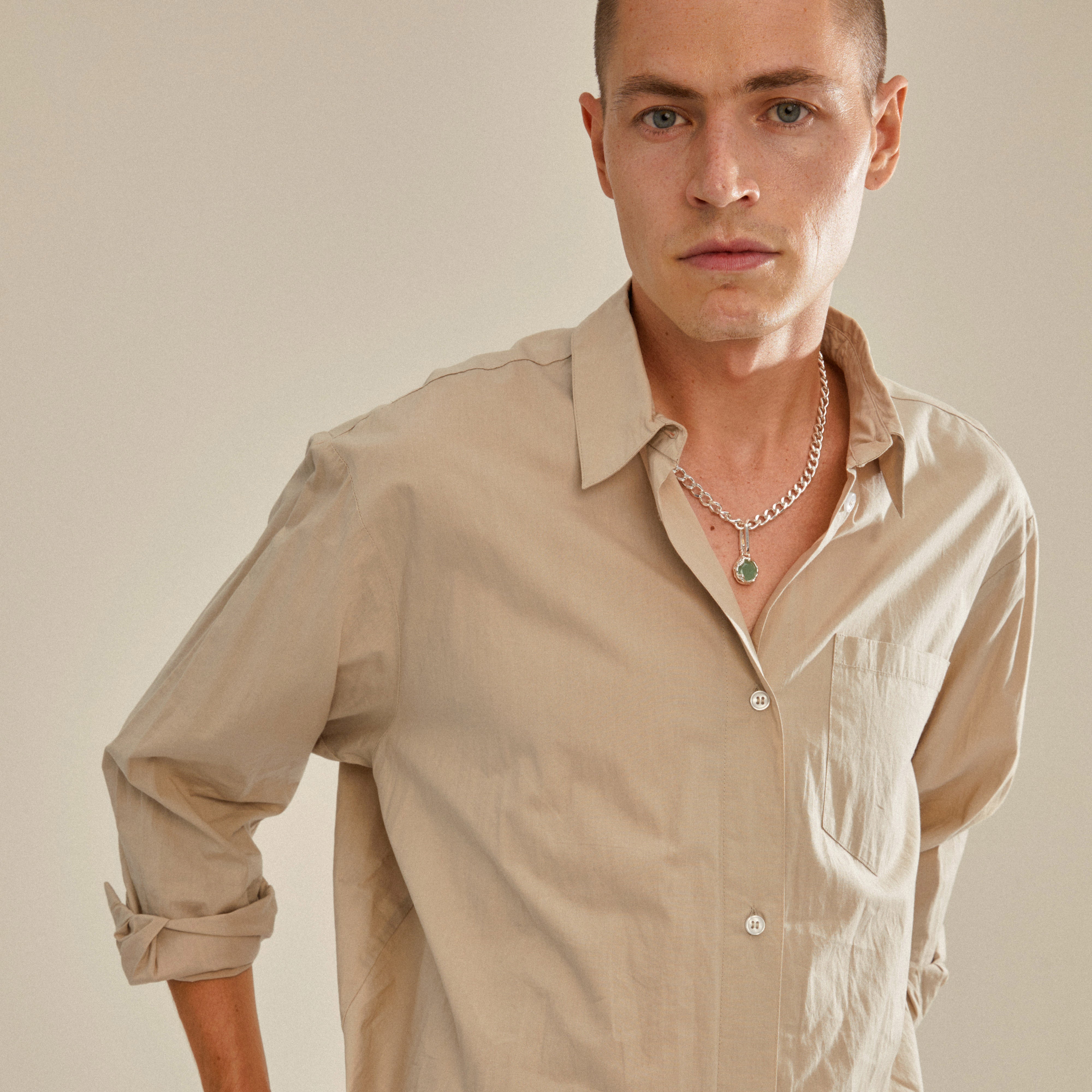 Man wearing a silver-plated CHARM natural pendant by Pilgrim, showcasing a green aventurine design on a chunky chain for personalized style.