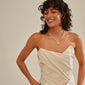 Woman with curly hair wears a white dress and smiles, showcasing a silver-plated yellow enamel heart pendant necklace, highlighting Pilgrim's charm collection.
