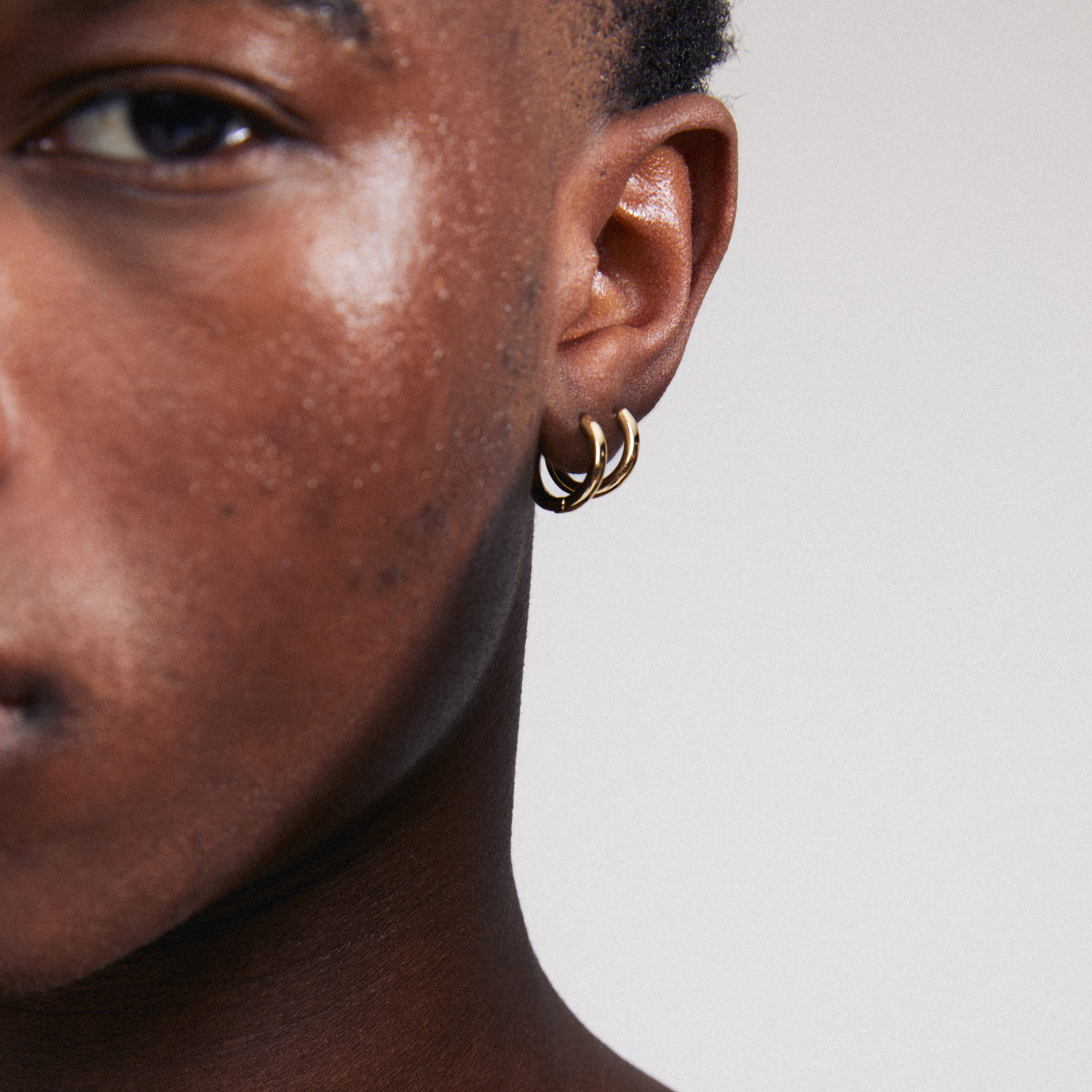 CHARM small hoop earrings gold-plated, worn on an ear, designed for adding charms, 15mm diameter, made from 99% recycled material for eco-friendly fashion.