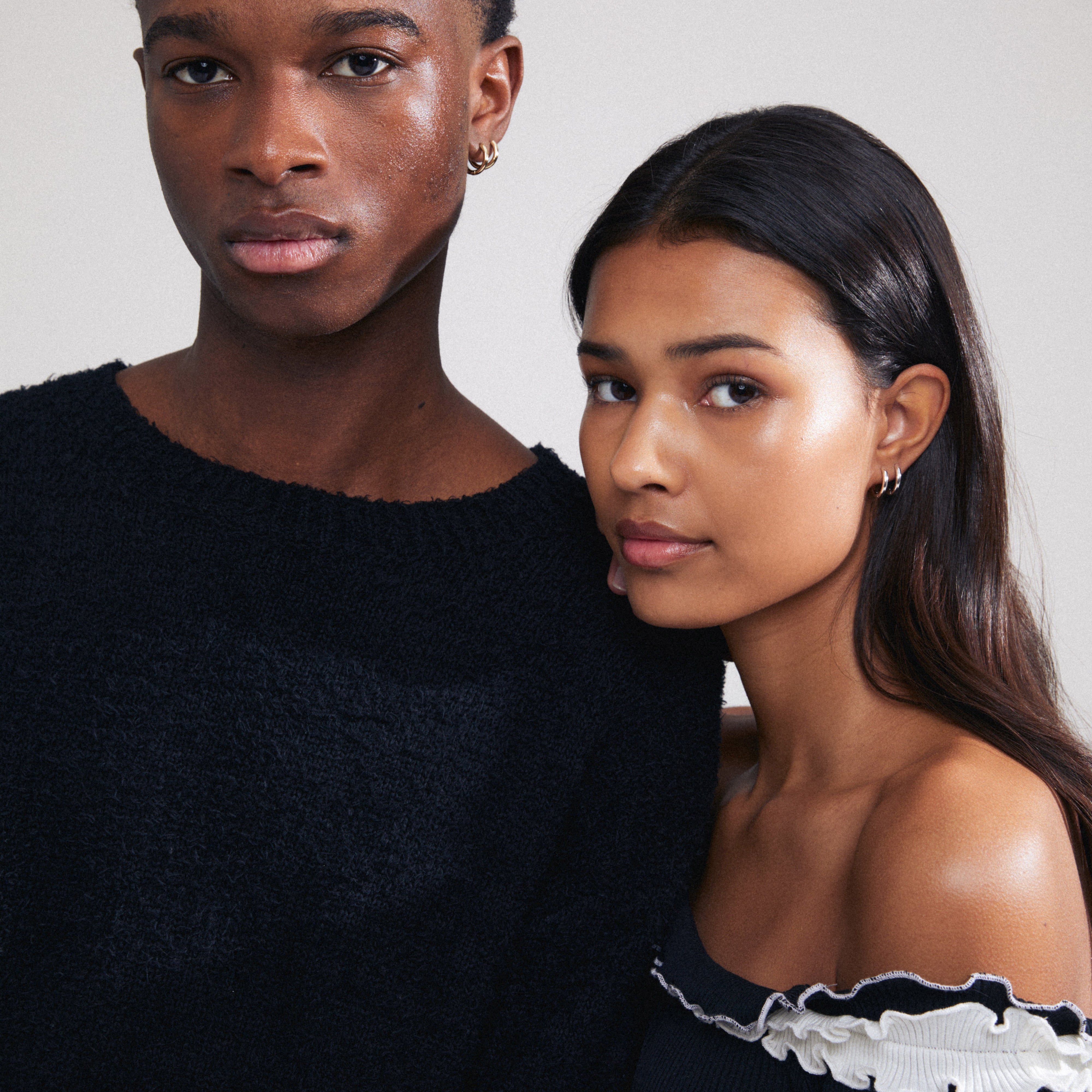 A man and woman showcase CHARM small gold-plated hoop earrings, ideal for personalizing with charms, emphasizing Scandinavian style and environmental consciousness.