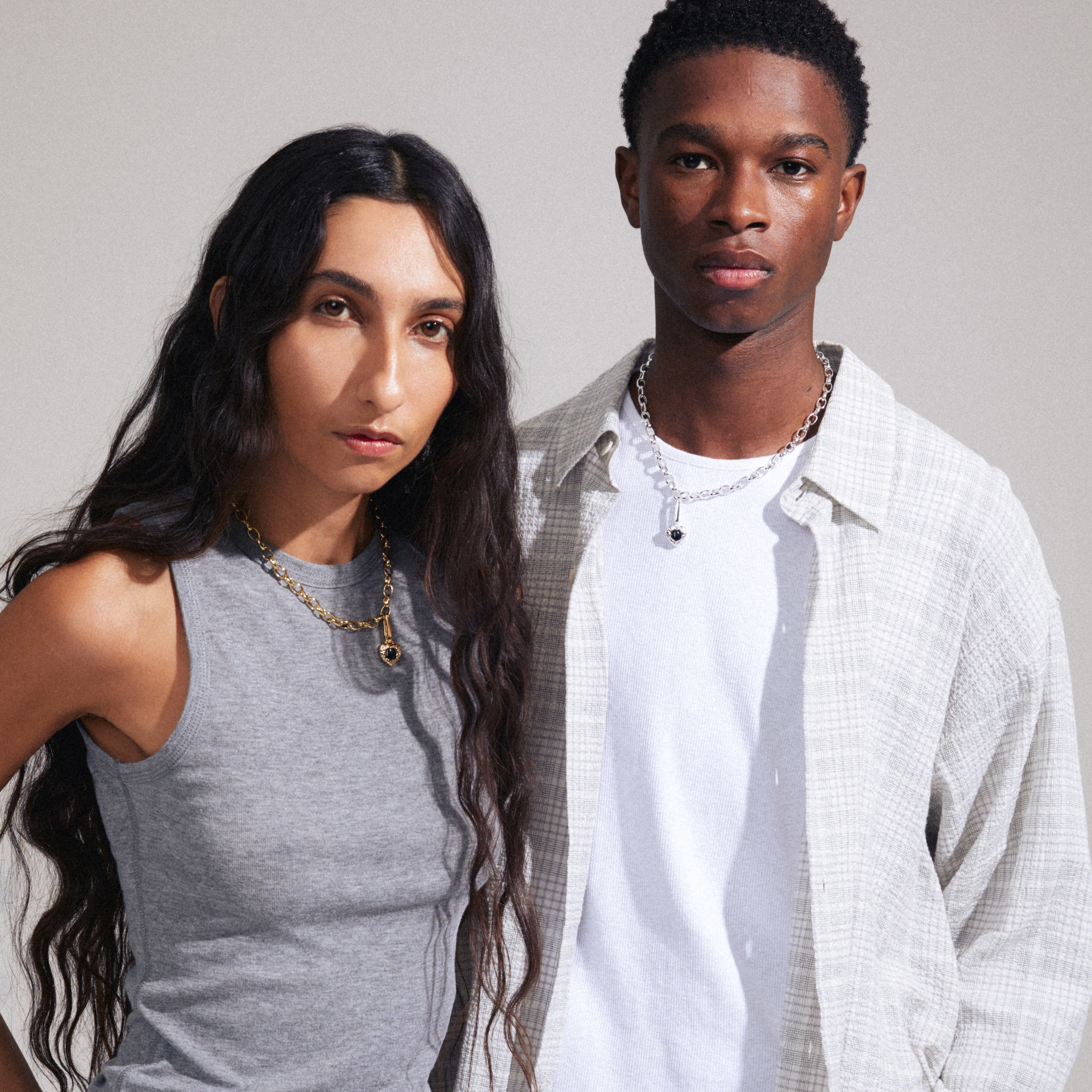Man and woman showcasing Pilgrim's CHARM black agate pendant, gold-plated, highlighting its versatility as a personalized accessory for unique styling.