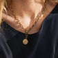 Woman wearing Pilgrim's CHARM horoscope pendant, a gold-plated medallion with zodiac symbols, accentuating personal style with its recycled material and Preciosa crystals.
