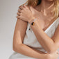 Woman wearing a white dress showcasing Pilgrim's CHARM bracelet, silver-plated with a cable chain design, perfect for adding charms and creating a trendy stacked look.